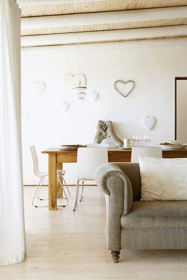 Romantische Herzdeko an der Wand eines Wohnzimmers mit hellem Dielenboden und Holzbalkendecke