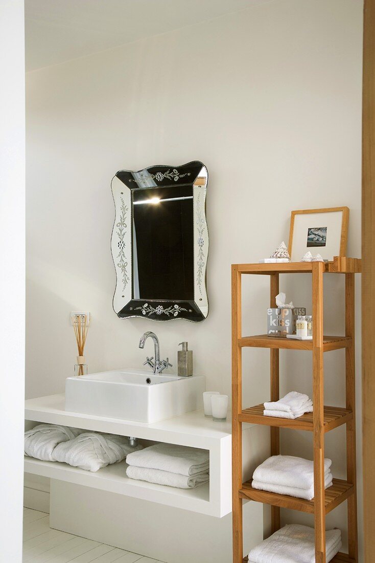Klassisches Badezimmerregal neben einem minimalistischen Waschtisch mit Handtuchablage und einem dekorativen Wandspiegel