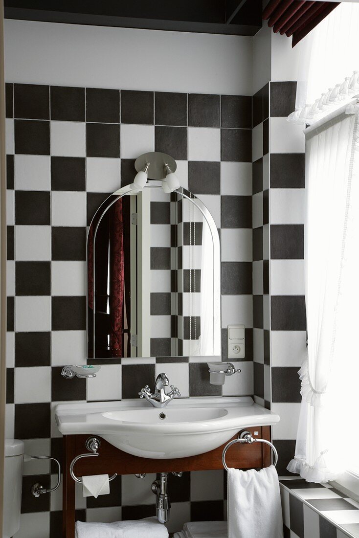 Eleganter Waschtisch und Badezimmerspiegel im schwarzweiss gefliesten Badezimmer