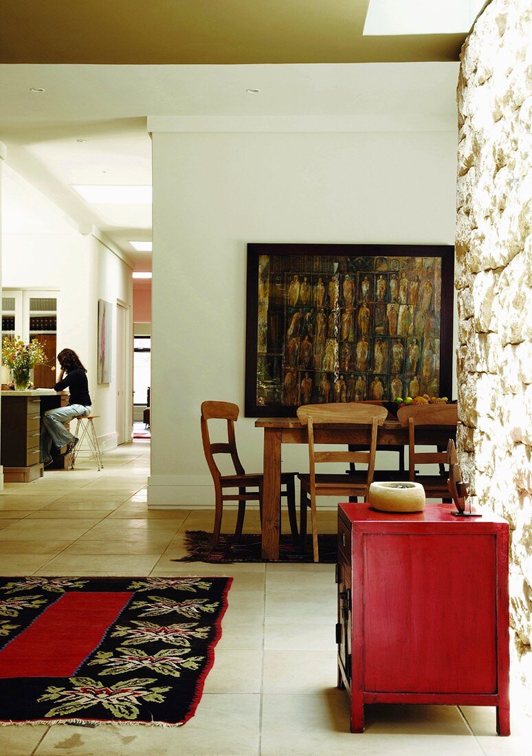 Biedermeierstühle am Esstisch vor einem abstrakten Ölgemälde im offenen Wohnraum mit roter Antikkommode