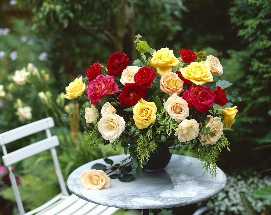 Vase of roses on marble table in garden