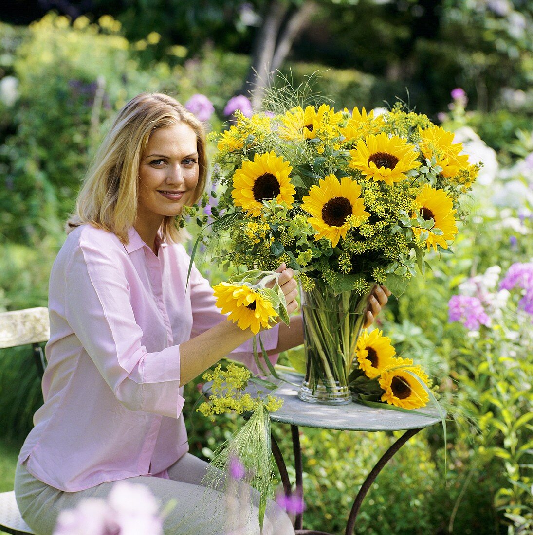 Young woman putting sunflowers in vase