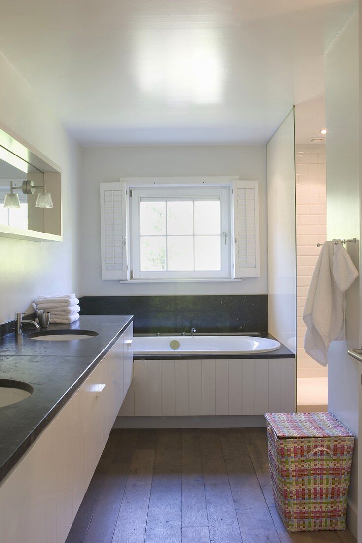 Badezimmer mit langem Waschtisch und einer Glastrennwand zum Duschbereich