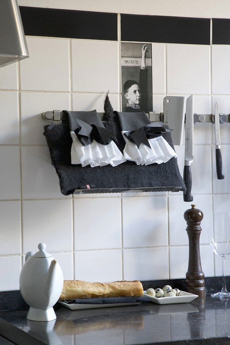 Küche mit schwarzer Arbeitsplatte mit darauf liegendem, frischem Baguette und Küchenutensilien in Schwarz und Weiß