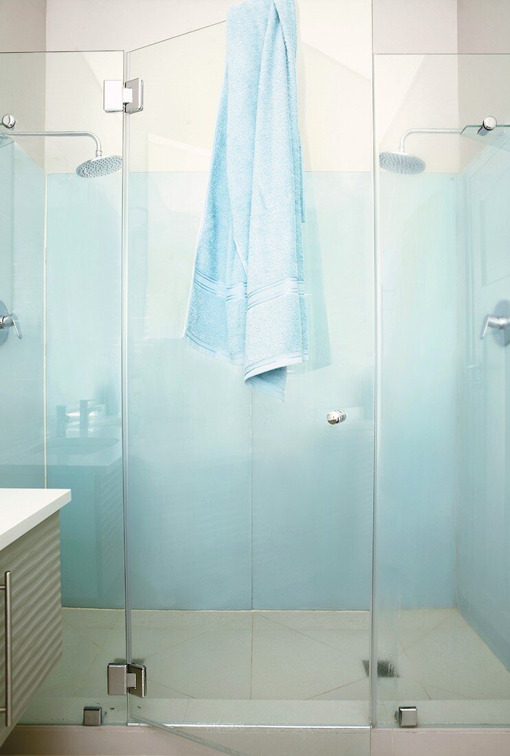 Pastellblaue Duschkabine mit gläsernen Trennwänden und gläserner Kabinentür