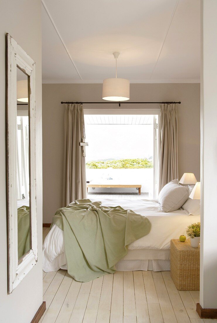 Schlafzimmer mit weiss lackiertem Holzdielenboden und mit direktem Blick auf die Terrasse