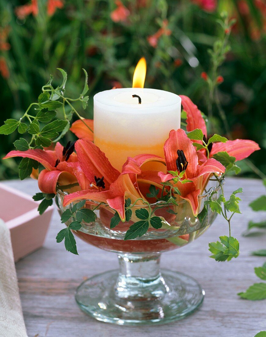 Glasschale mit Kerze, Taglilie und Waldrebe