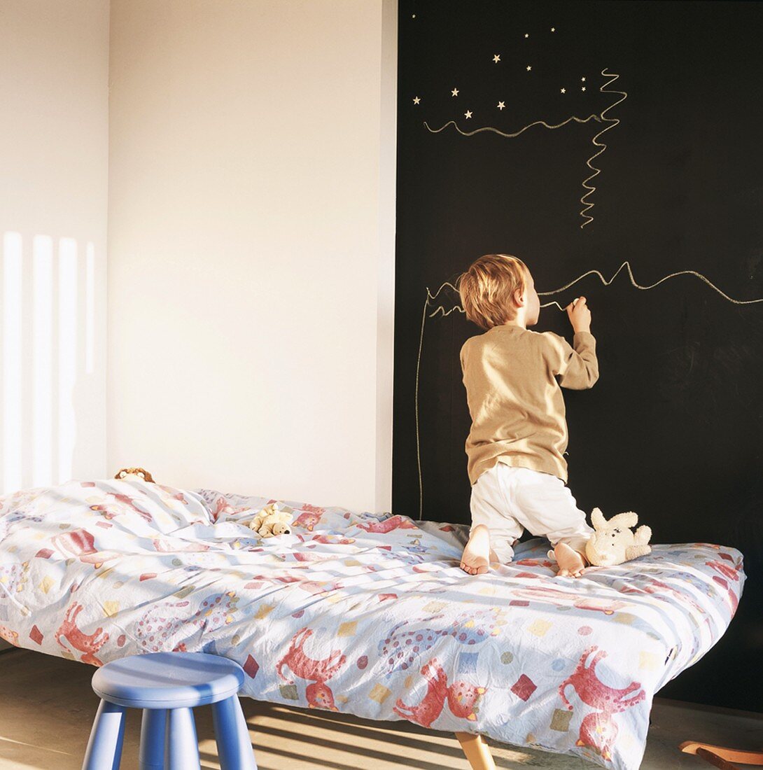 Kinderzimmer mit großer Wandtafel und zeichnendem Kind