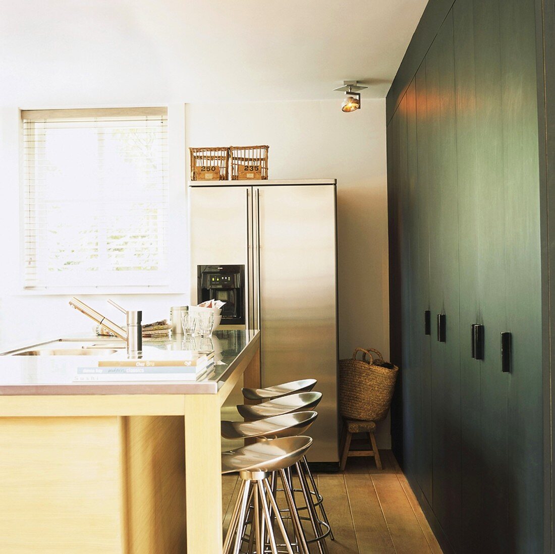 Küchenblock mit metallenen Barhockern vor Schrankwand