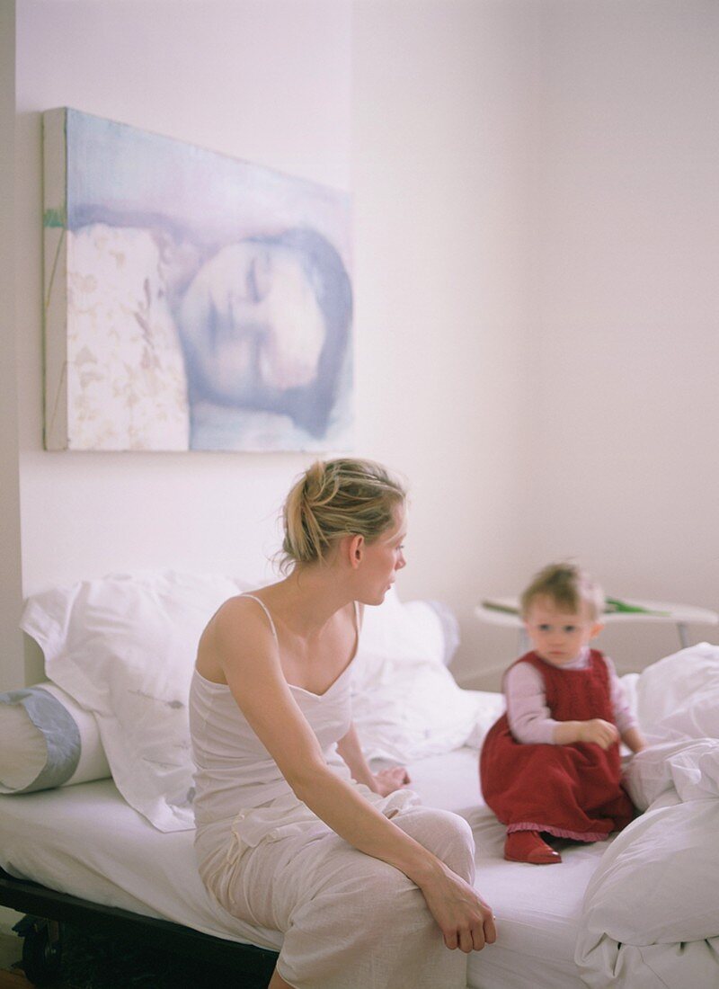 Mutter und Kind im Gespräch auf dem Bett sitzend