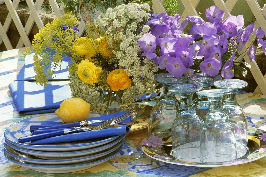Crockery, cutlery and flowers on table out of doors