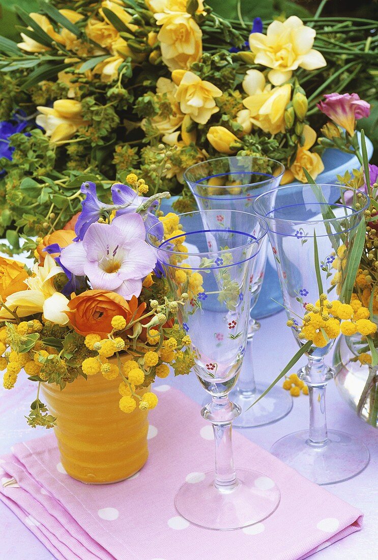 Bunches of summer flowers with sparkling wine glasses out of doors