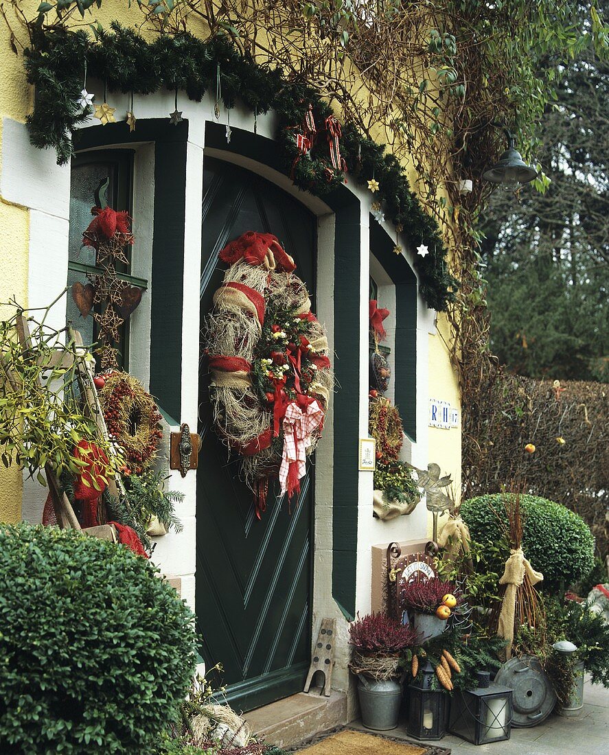 Weihnachtlich dekorierte Haustür mit verschiedenen Kränzen & Tannengirlande