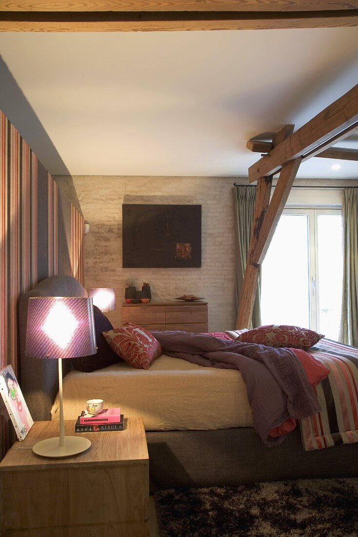Beleuchteter Schlafraum mit Holzbalken, Bett & Nachttischlampen
