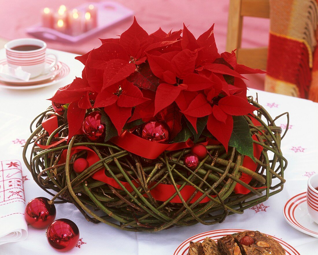 Poinsettia in a willow wreath with Christmas baubles