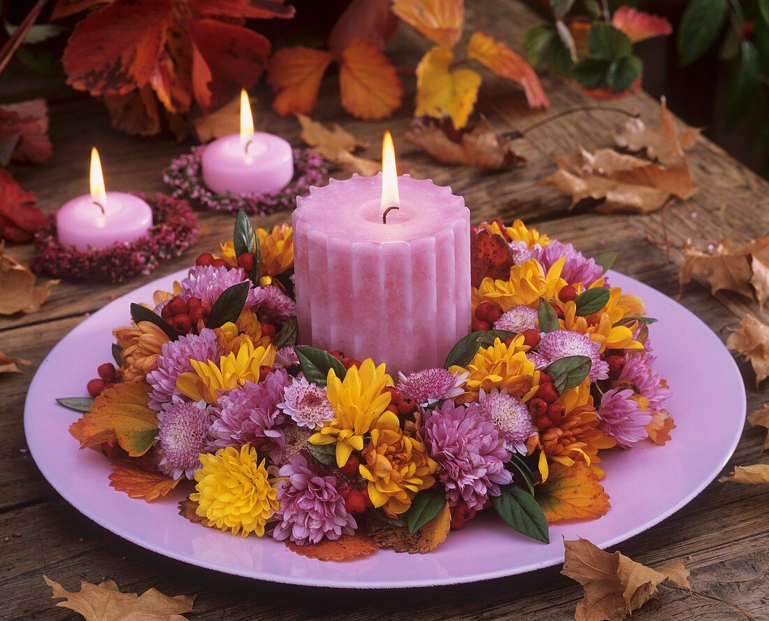 Kranz aus Herbstchrysantemen,Cotoneaster und Kerze auf Teller