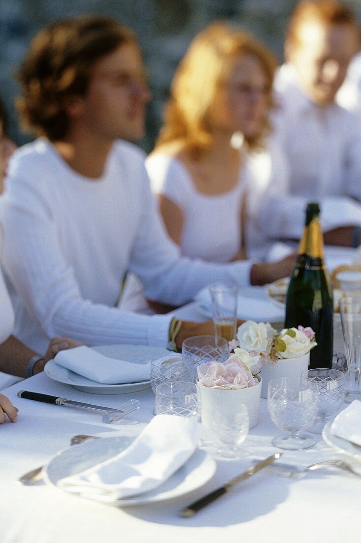 Freunde sitzen an festlich gedecktem Tisch mit Champagner