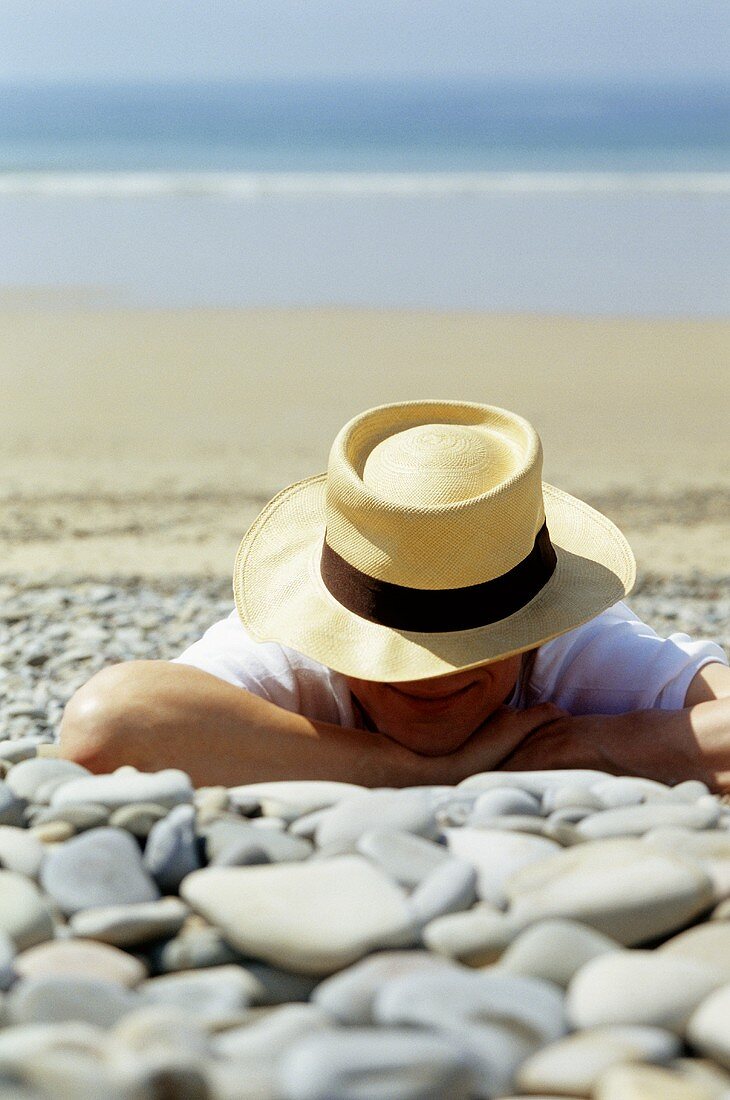 Man in hat lying on beach