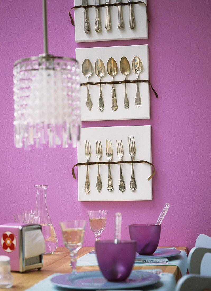 Laid table, display of cutlery on pink wall