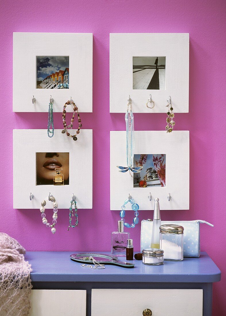 Jewellery hanging on picture frames above a chest of drawers