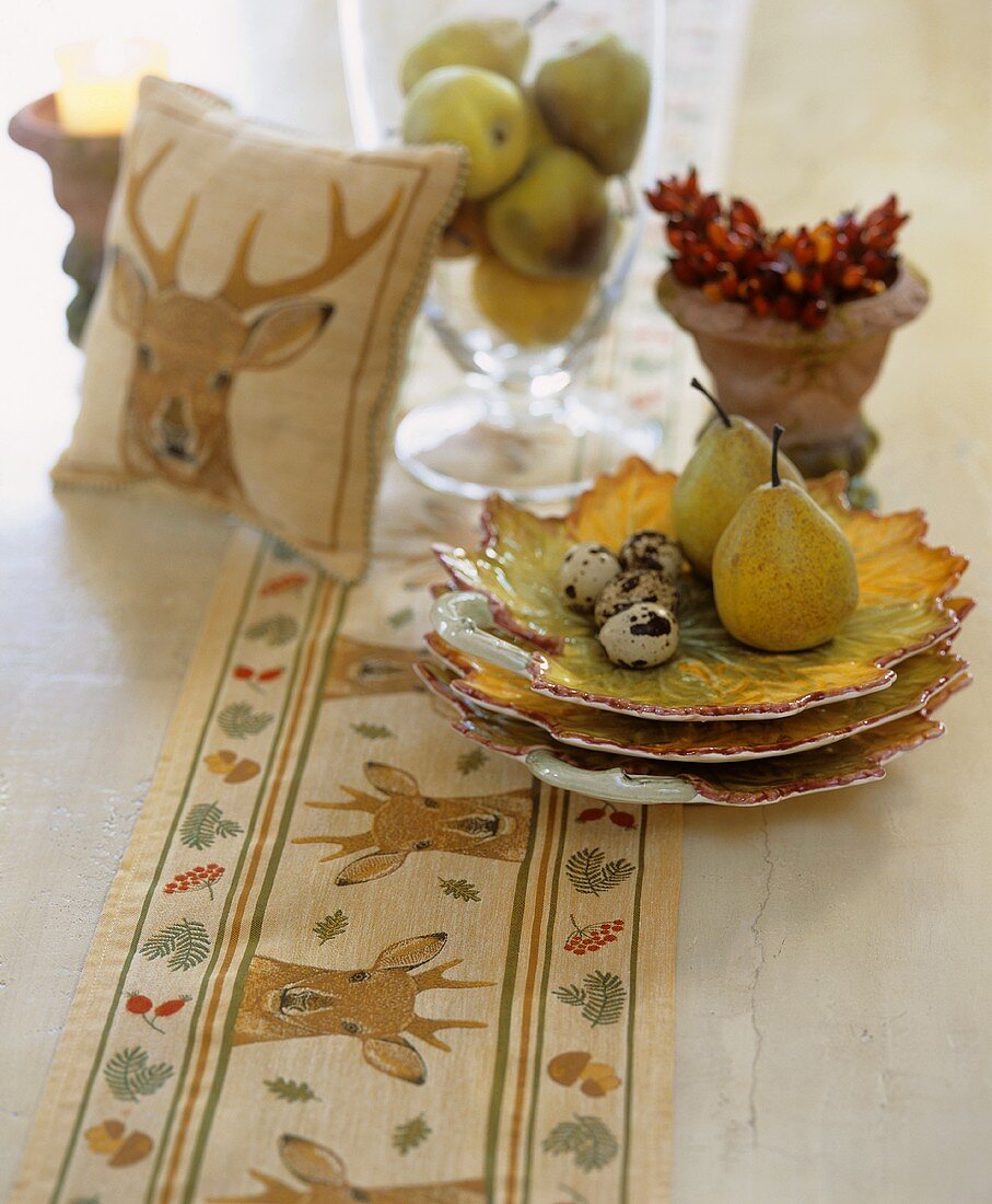 Pears, quails' eggs and autumnal decorations on table