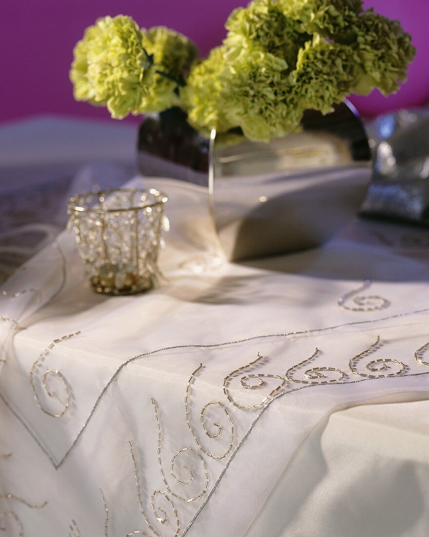 Weiß-silberfarbener Tisch mit Blumendeko