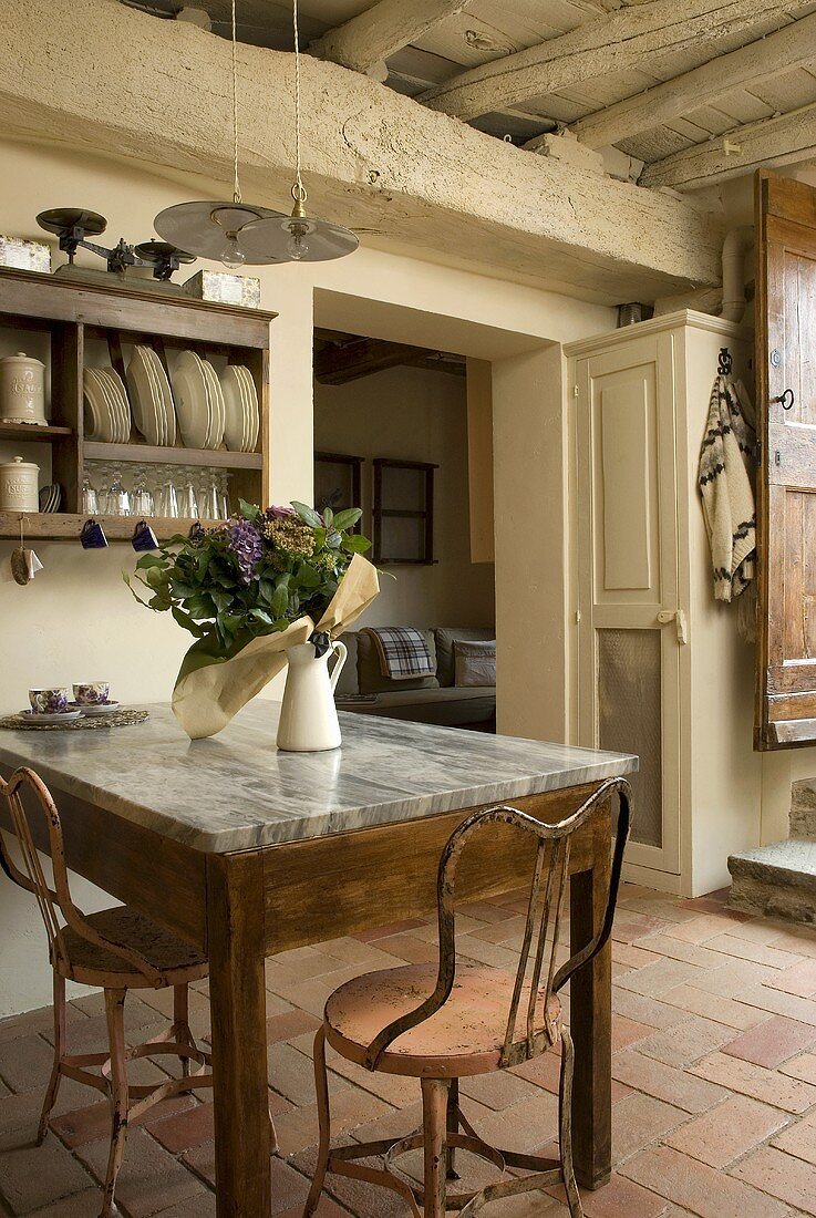 A dining table with a marble top and a Mediterranean terracotta floor in a rustic country house