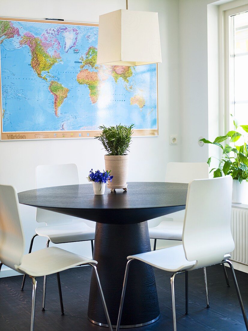 Runder Tisch mit Stühlen und Weltkarte im Hintergrund