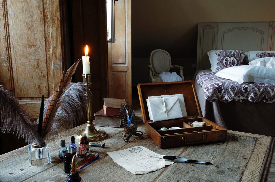 Briefpapier, Schreibfedern, Tinte & Kerzenständer auf Holztisch im Schlafzimmer