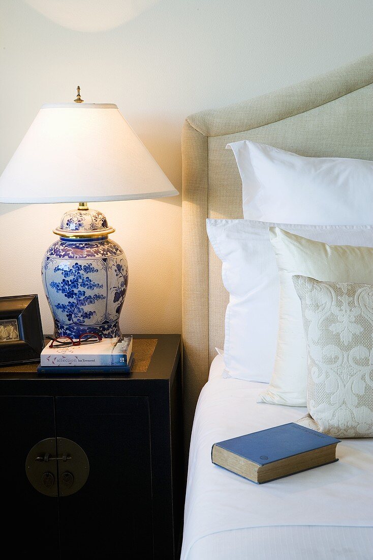 Lampe mit blau-weißem Porzellanfuss auf Beistelltisch neben Bett