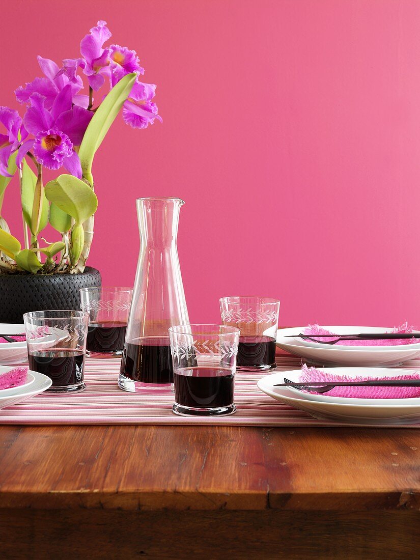Gedeckter Tisch mit Rotwein und Cattleya-Orchidee
