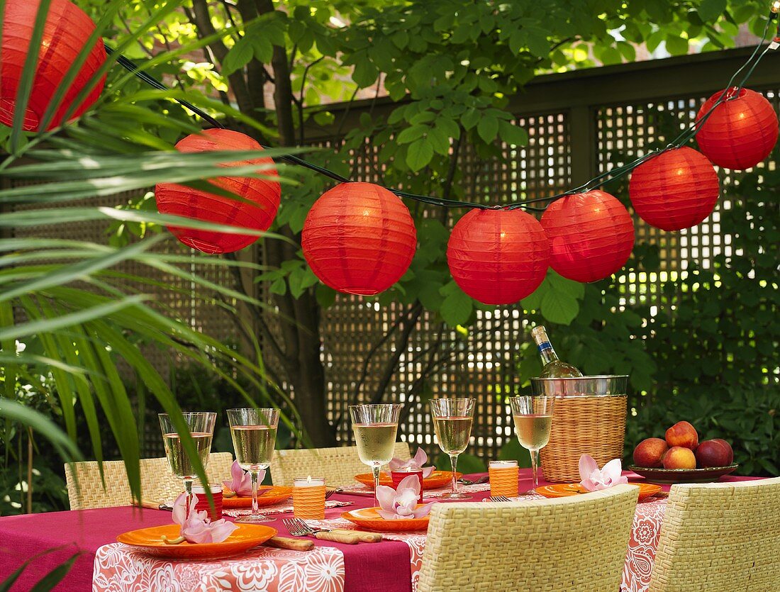 Festive table with white wine & Chinese lanterns out of doors