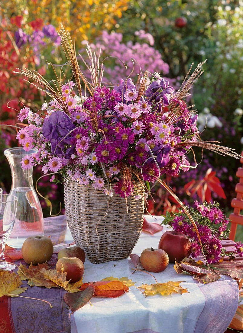 Tisch mit Strauss aus Herbstastern, Äpfeln und Herbstlaub