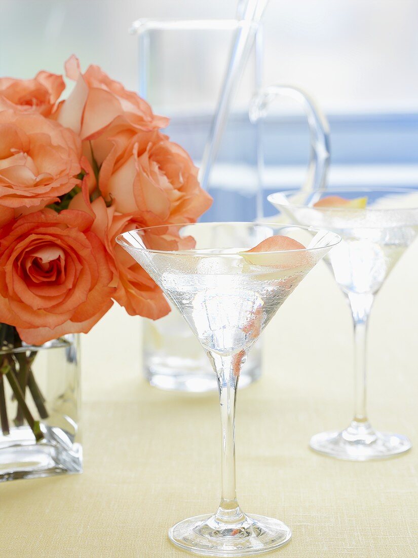 Two glasses of Martini with rose petals, vase of roses