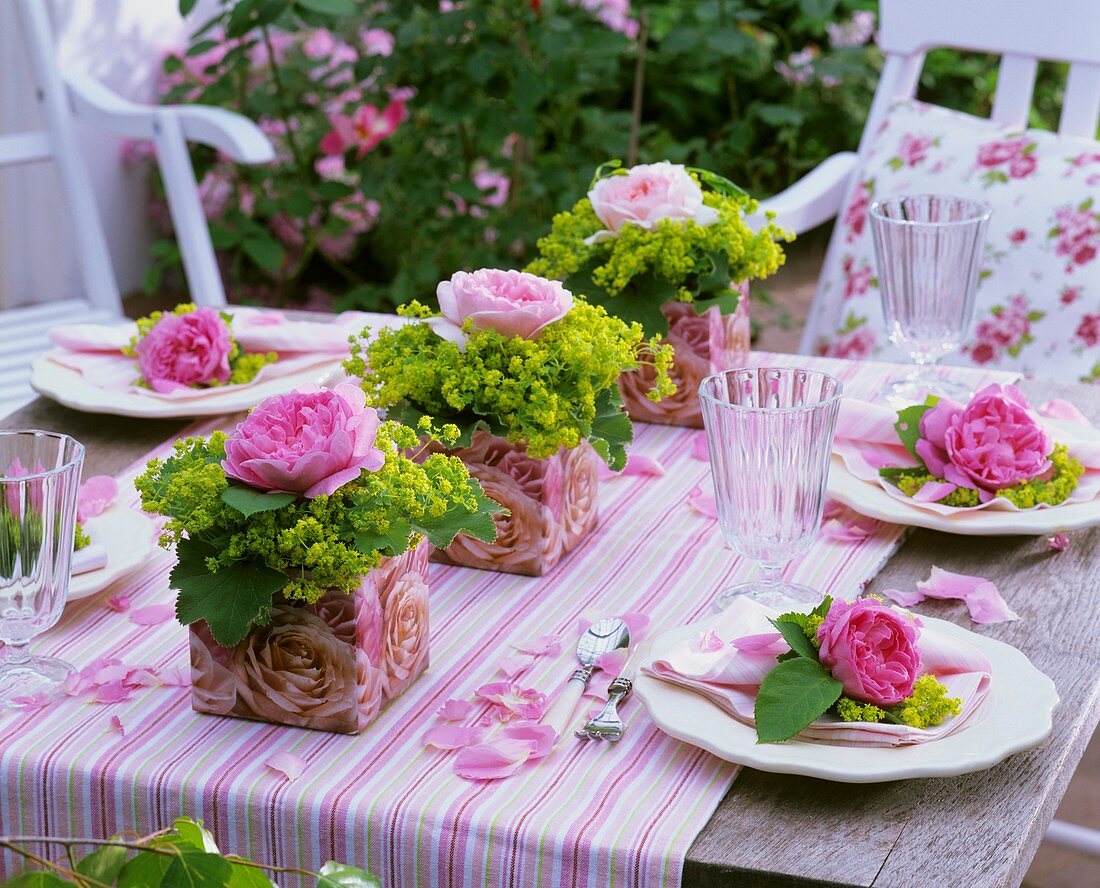 Gedeckter Tisch mit Rosen und Frauenmantel dekoriert
