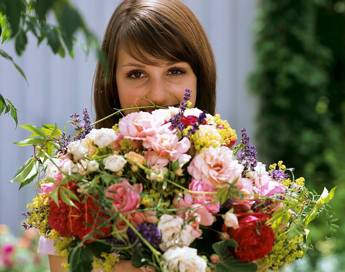 Frau hält Strauss aus Rosen, Frauenmantel und Lavendel