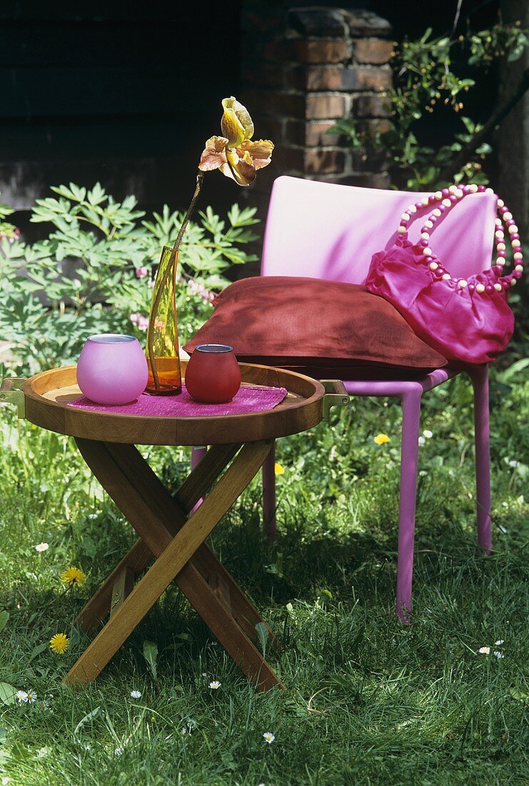 Gartentisch und rosa Gartenstuhl mit Kissen und Tasche
