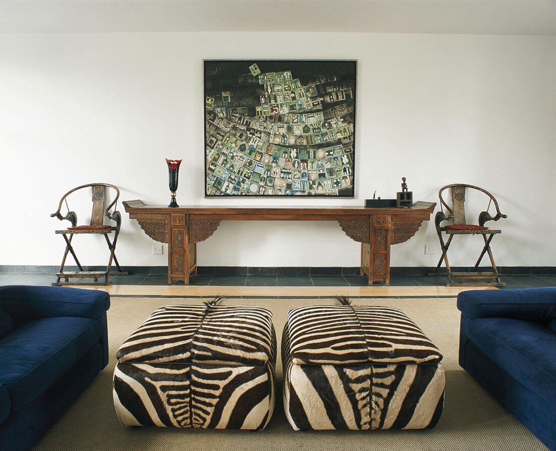 Wohnzimmer mit Polsterhockern im Zebra-Look, länglichem Konsolentisch & modernem Wandgemälde