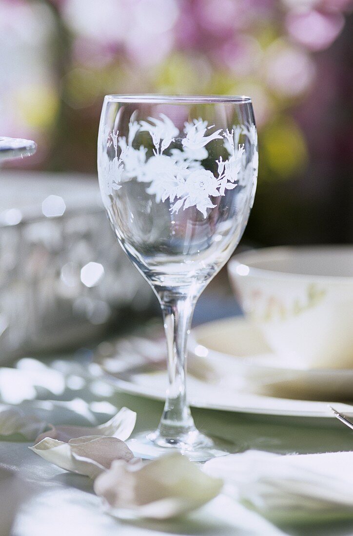 Ein Weinglas auf Tisch mit Blütenblättern