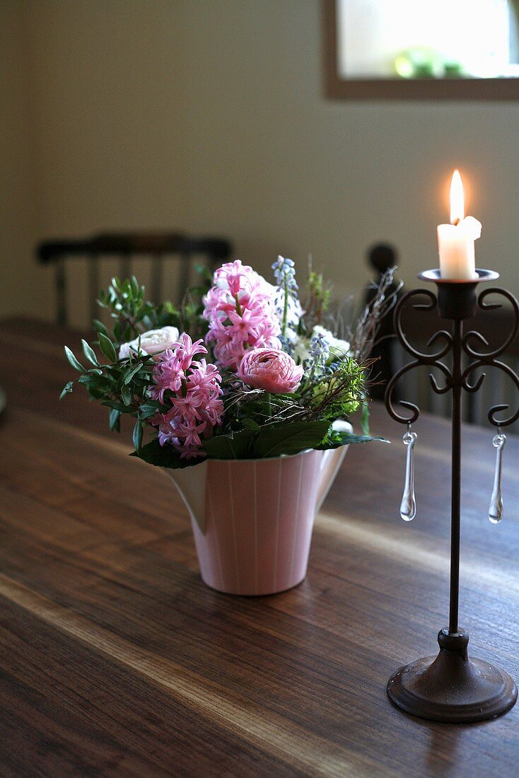 A bunch of flowers and a candle on a wooden table