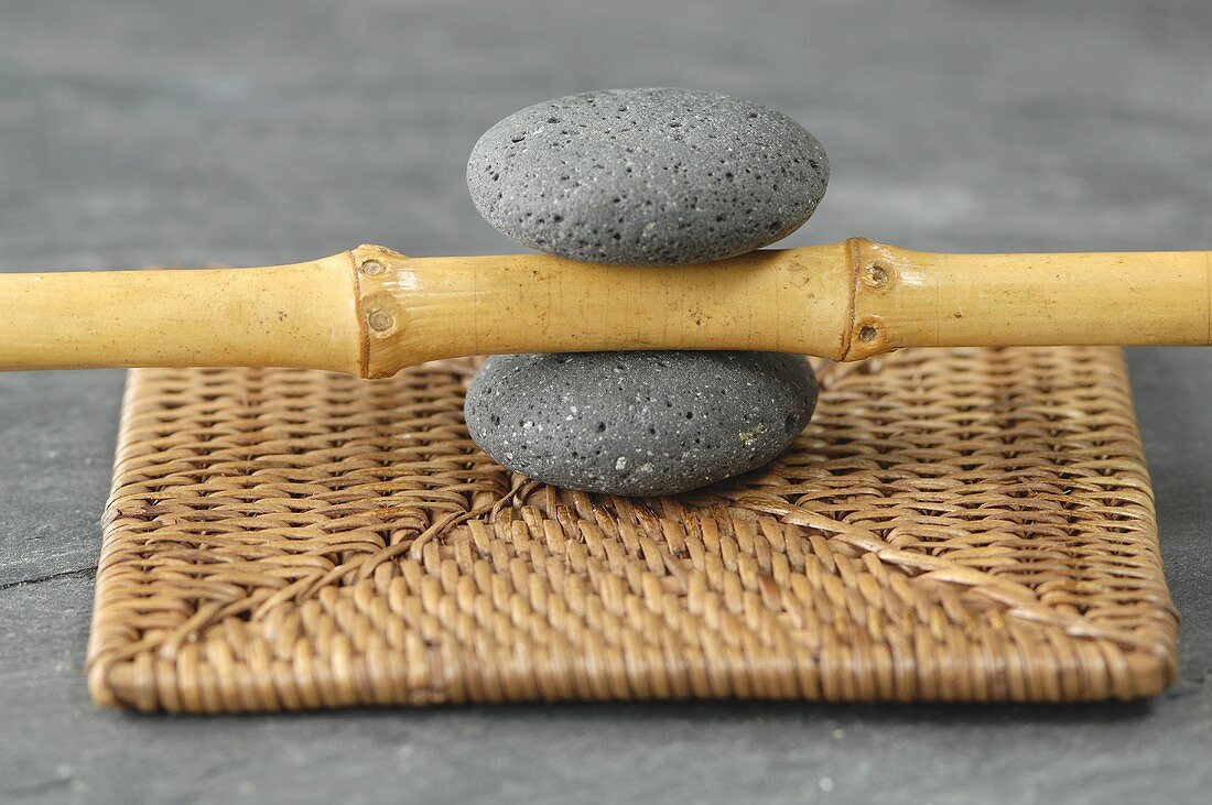 A bamboo stick between two pebbles on a place mat