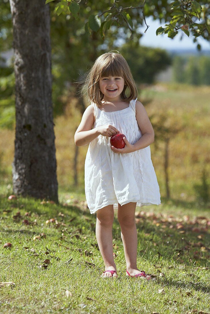 A little girl holding an apple