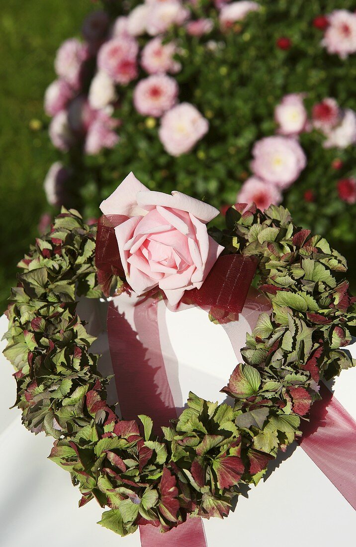 A heart-shaped wreath of hortensia flowers with a rose