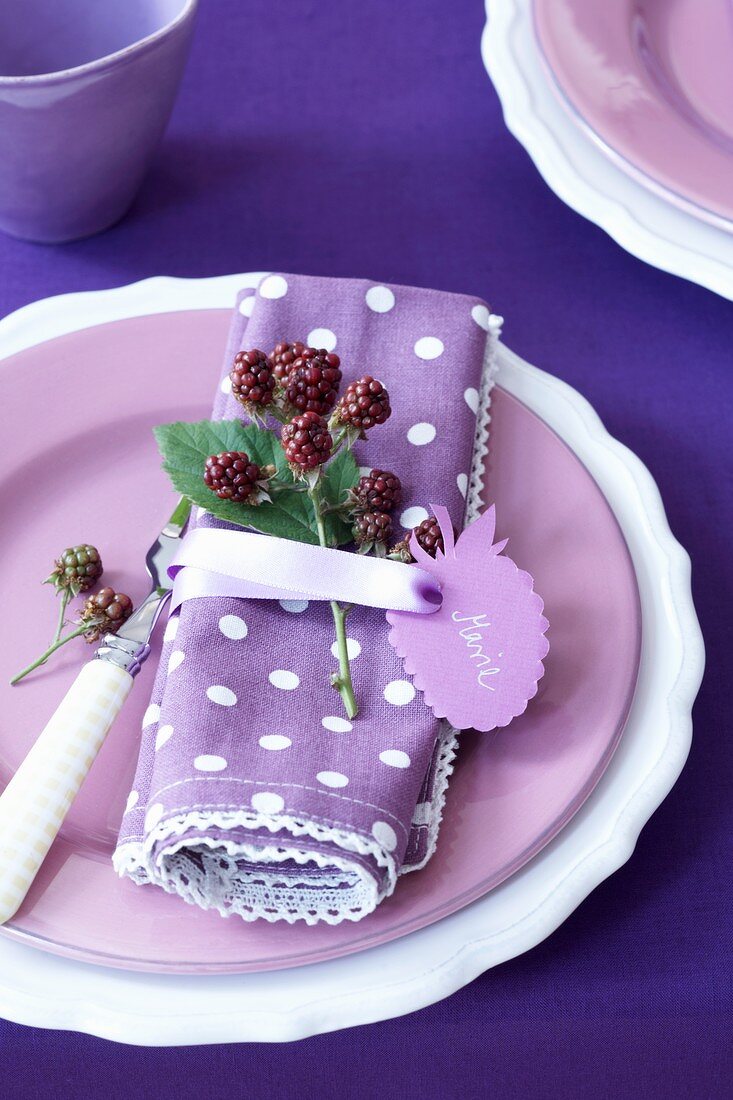 A place setting with a sprig of black berries