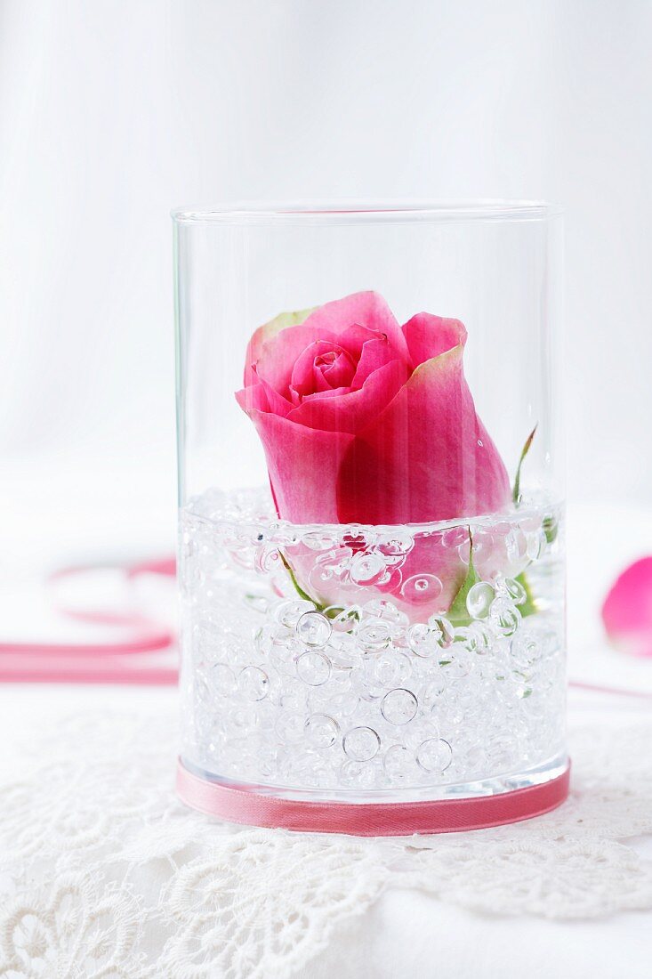 Rose im Glas mit Dekosteinen