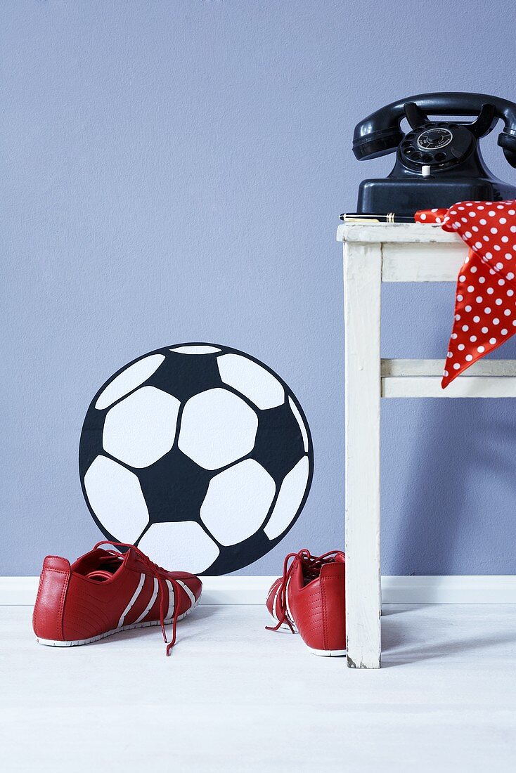 A football wall sticker, football boots and an old telephone