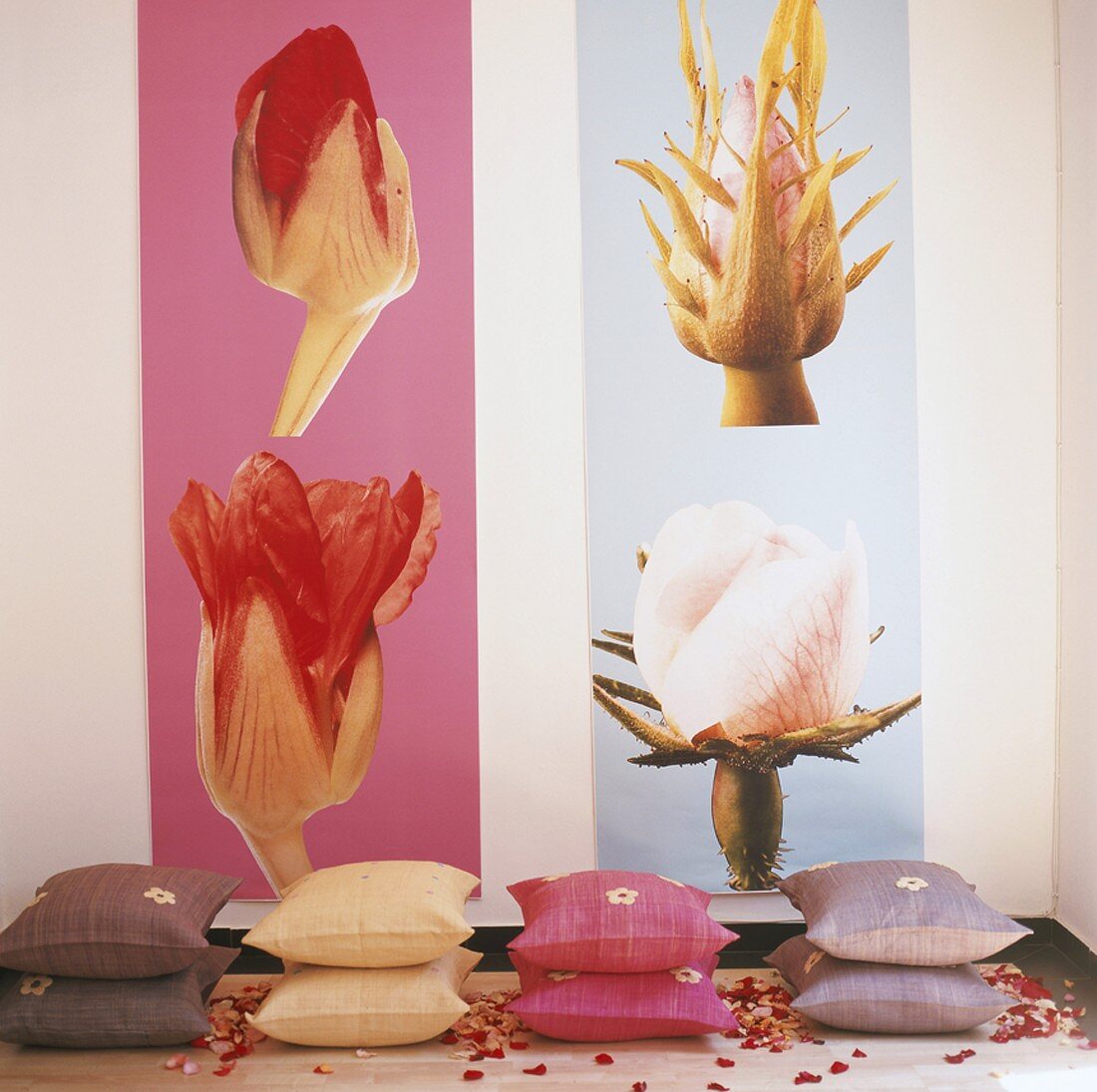 Gestapelte Zierkissen vor Bilderwand mit Blütenmotiven