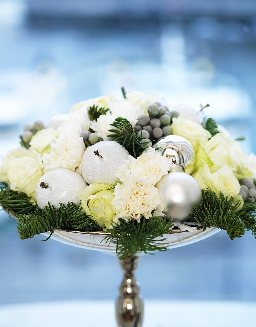 Xmas table decoration: white flowers, fir sprigs, candles, baubles