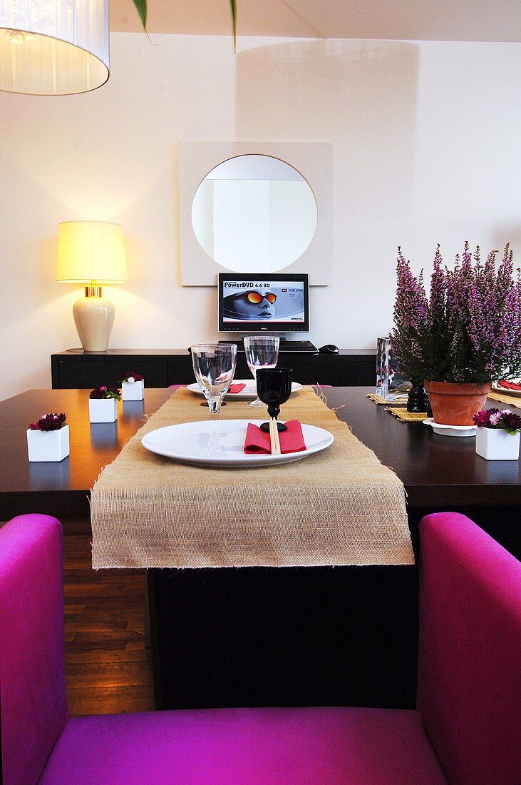 Blick auf gedeckten Esstisch mit pinkfarbenem Stuhl