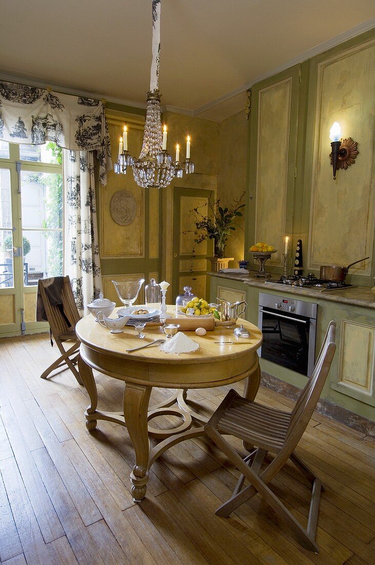 Küche mit grüner Holzvertäfelung, rundem Tisch & Kronleuchter